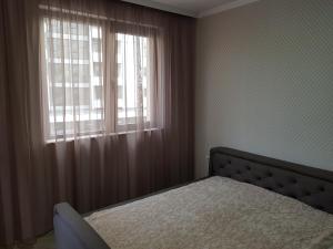 a bedroom with a bed and a window at Хепи Апартмънтс in Plovdiv