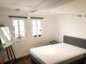 a bedroom with a white bed and two windows at Hexenhäuschen Dreieichenhain in Dreieich