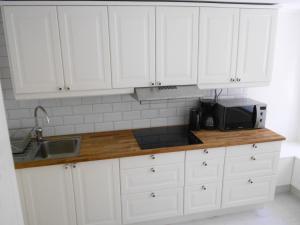 una cucina con mobili bianchi, lavello e forno a microonde di Townhouse Lund a Lund