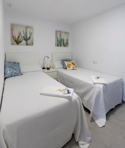 Dos camas en una habitación con paredes blancas. en Alameda Home Pontevedra, en Pontevedra