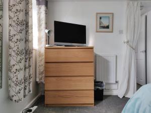 a bedroom with a dresser with a television on it at Garden Apartment in Newton Abbot