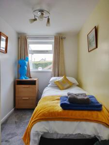 a bedroom with a bed with a yellow blanket and a window at Garden Apartment in Newton Abbot
