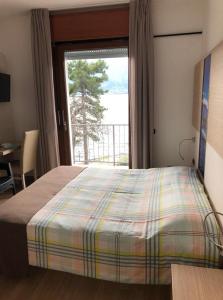 een slaapkamer met een bed en een groot raam bij Albergo Campeggio Bommartini in Malcesine