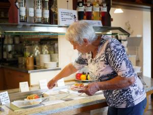 une femme préparant une assiette de nourriture sur un comptoir dans l'établissement Hotel Lenauhof, à Bad Birnbach