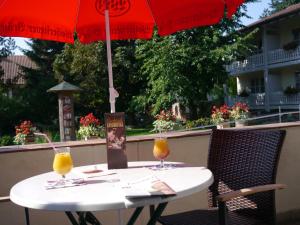 - une table avec deux verres de jus d'orange et un parapluie dans l'établissement Hotel Lenauhof, à Bad Birnbach