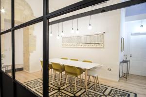 ein Esszimmer mit einem weißen Tisch und gelben Stühlen in der Unterkunft Orma Design Rooms - Historic centre in Cagliari