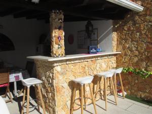 a bar with white stools in front of a stone counter at Casa da Boa Agua 1 in Quinta do Conde