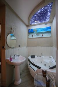 een badkamer met een bad, een wastafel en een spiegel bij Pensione Enea in Napels