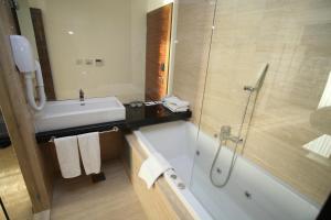 a bathroom with a tub and a sink and a shower at Beach Hotel Split in Podstrana