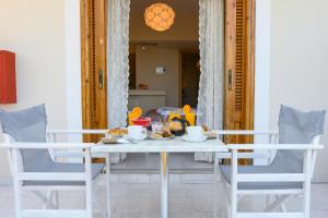 una mesa de comedor con sillas y comida. en Maria Apartments Studios Epidavros, en Palaia Epidavros