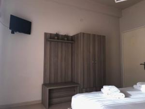 a room with two beds and a cabinet and a television at Siviri Rooms in Siviri