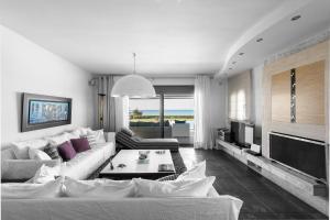 a living room with a white couch and a tv at Possidi Villa Glamour by Luxlikehome in Possidi
