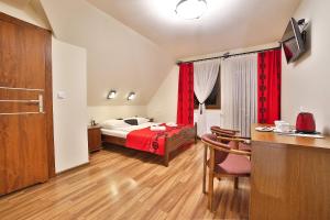 a bedroom with a bed with red curtains and a table at Grand Podhale Resort&Spa Zakopane - Jacuzzi - Sauna fińska i Łaźnia parowa - Widok na Tatry in Zakopane