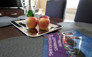een bord met drie appels op een tafel met een boek bij Apartament Zielone Tarasy 9C in Kołobrzeg