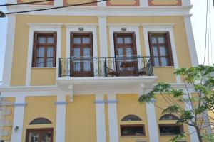 a yellow building with windows and a balcony at Myrtia in Symi