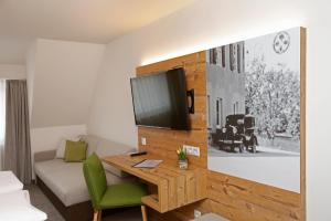a hotel room with a desk and a tv on a wall at ApartHotel Rose in Ellwangen +42 photos