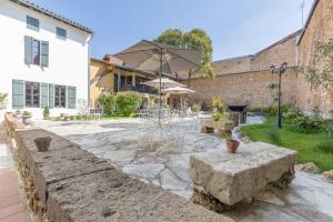 une terrasse en pierre avec une table et un parasol dans l'établissement Le Logis d'Augustin, à Mont-de-Marsan