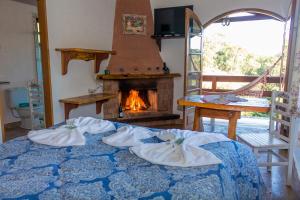 a bedroom with a fireplace and a bed with towels at Pousada Canto dos Pássaros in Santo Antônio do Pinhal