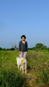 a woman standing next to a dog in a field at Jungle House in Yala