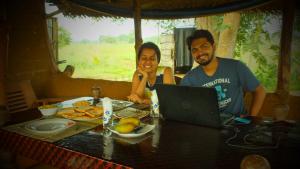 un hombre y una mujer sentados en una mesa con un portátil en Jungle House, en Yala