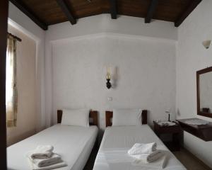 two beds in a room with white walls at Katerina Apartments in Kato Zakros