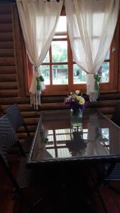 a glass table with flowers in a room with a window at Cabaña Alamos Altos in Belén de Escobar