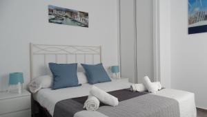 1 dormitorio con 1 cama grande con almohadas azules y blancas en apartamento rio salado, en Conil de la Frontera