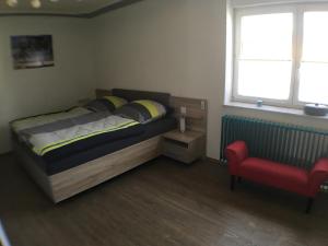 a bedroom with a bed and a red chair at Ferienwohnung Alte B3 in Ringsheim