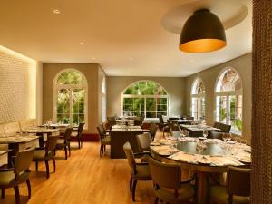 Un comedor con mesas y sillas y ventanas. en Royal Palm Plaza Resort, en Campinas