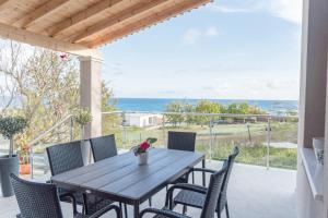 a table and chairs on a patio with a view of the ocean at Villa Aelia Gardeno in Vitalades