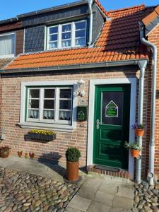 una casa de ladrillo con una puerta verde y ventanas en Ein kleines Haus en Fehmarn