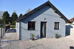 a blue shed with two windows and two potted plants at Le Chalet de l'Authie in Saulchoy