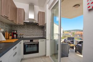 une cuisine avec des placards blancs et une vue sur un balcon. dans l'établissement City Apartment Magdalena, à Trogir