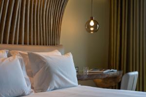 a bedroom with a bed with white pillows and a table at Vila Foz Hotel & SPA - member of Design Hotels in Porto