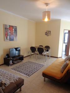 a living room with a table and chairs and a television at Apartamento Praia dos Salgados in Albufeira
