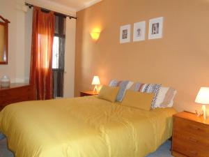 1 dormitorio con 1 cama amarilla y 2 lámparas en Apartamento Praia dos Salgados, en Albufeira