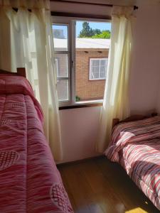 a bedroom with two beds and a window at Complejo La Naranjita in Rosario