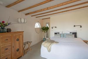 een slaapkamer met een wit bed en een houten dressoir bij Studio Haarlemenmeer in Cruquius