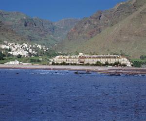 a hotel on the beach with mountains in the background at Hotel Gran Rey in Valle Gran Rey