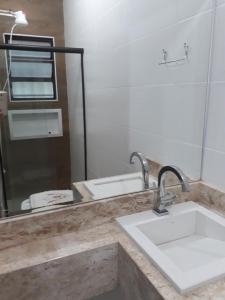 een badkamer met een wastafel en een spiegel bij CASA ESPAÇOSA 4 DORMITÓRIOS A 150M DA PRAIA DA MARANDUBA / UBATUBA in Ubatuba