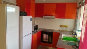 a kitchen with red cabinets and a white refrigerator at le petit coin de paradis in Sainte-Anne