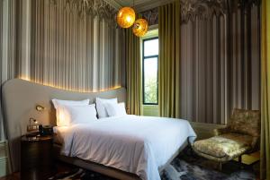 a bedroom with a bed and a chair and a window at Vila Foz Hotel & SPA - member of Design Hotels in Porto