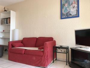 uma sala de estar com um sofá vermelho e uma televisão em Goelands em Palavas-les-Flots