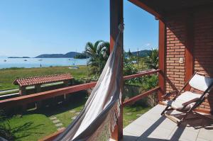 um alpendre com uma rede de descanso e um banco numa casa em Casa Inteira frente mar em Paraty