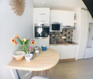 a small kitchen with a wooden table with flowers on it at La Madeleine in Vannes