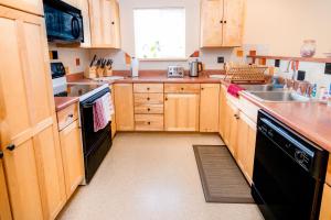 a kitchen with wooden cabinets and a black dishwasher at Talkeetna Hideaway in Talkeetna
