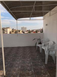 a patio with white chairs and a table on a roof at Pousada Tchê Aprochega in Pelotas
