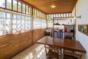 a kitchen with a wooden table and some windows at Casa Inteira frente mar in Paraty