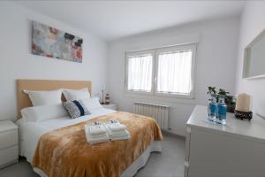 Un dormitorio blanco con una cama con toallas. en Alameda Home Pontevedra en Pontevedra