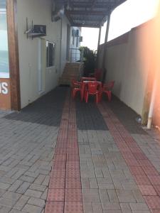 JH santos في تشابيكو: فناء به طاولات حمراء وكراسي على مبنى